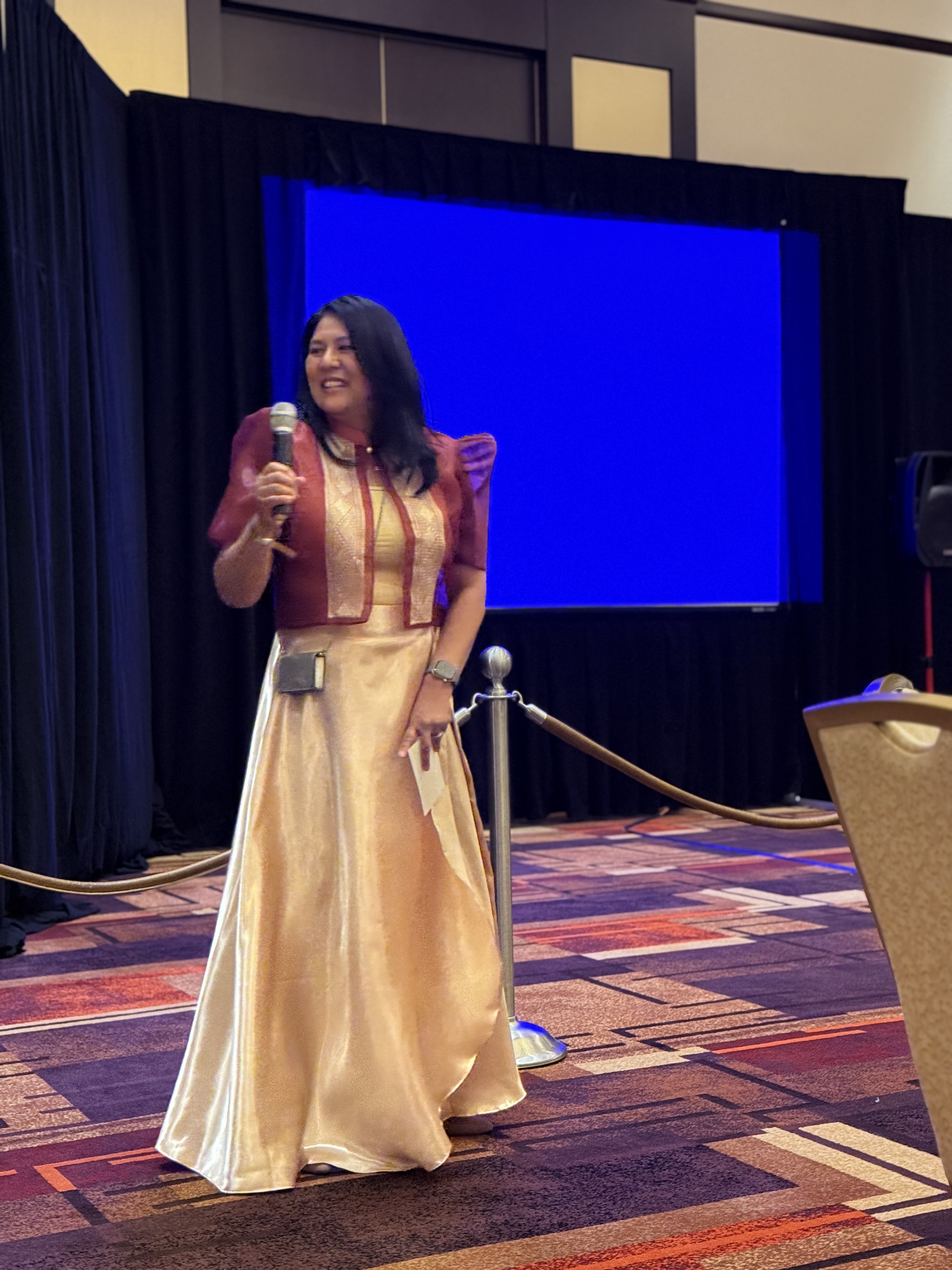 Dr. Victoria Squier speaking on stage, holding a microphone